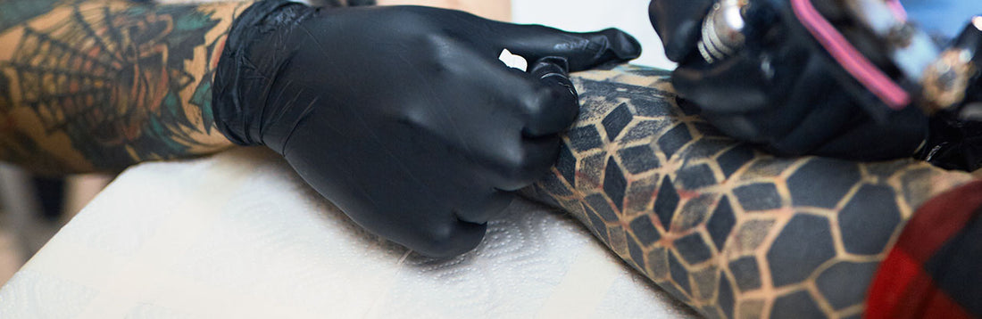 tattoo artist working in a black nitrile glove