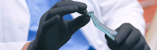 person wearing black nitrile gloves and holding a tool