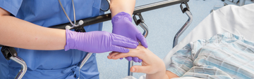 nurse attending to a patient while wearing grape grip nitrile exam gloves