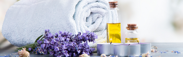 massage oil, tea candles, lavender and a towel laid out on a table
