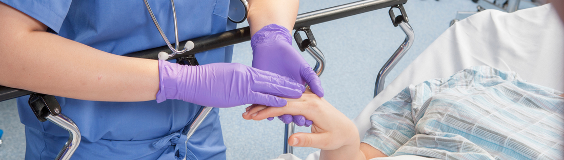 nurse caring for patient while wearing purple nitrile grape grip gloves