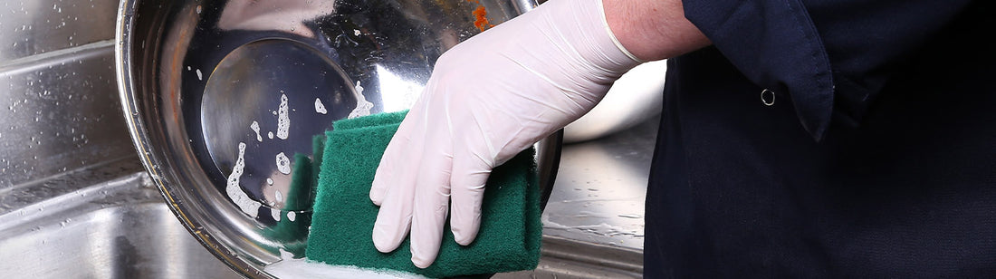 person wearing white latex glove and washing dishes