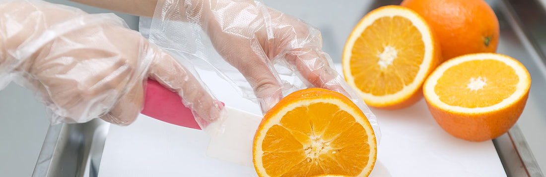 person wearing poly gloves and slicing oranges