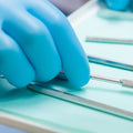 person wearing blue nitrile gloves and touching dental tools