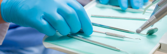 person wearing blue nitrile gloves and touching dental tools