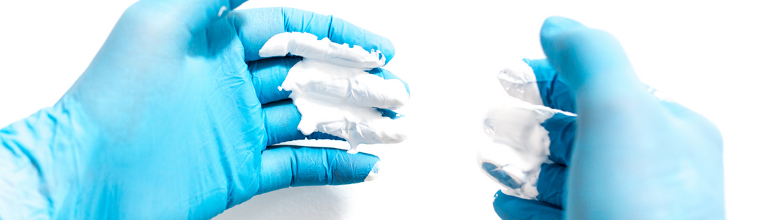 person wearing blue nitrile gloves with white paint on them