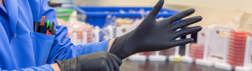 Person pulling on black nitrile gloves