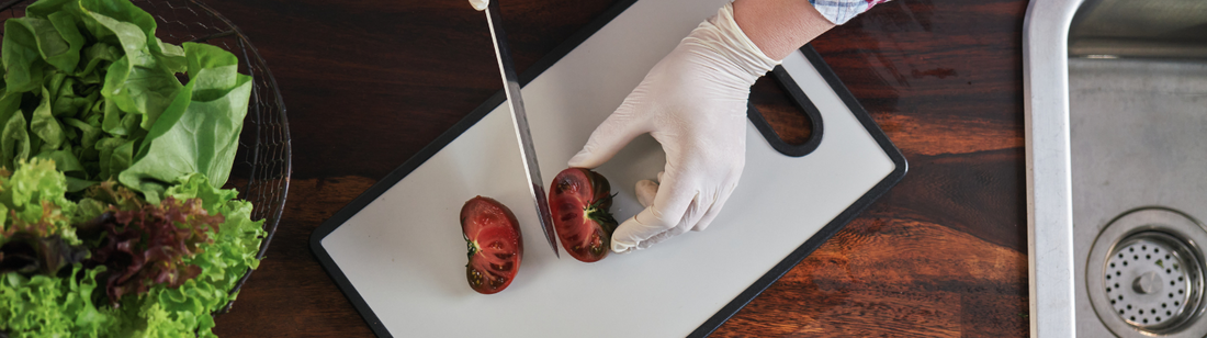 person wearing pvc vinyl gloves and cutting produce