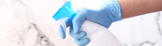 person in light blue nitrile gloves gripping a spray bottle
