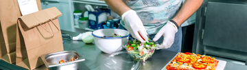 person wearing thin white nitrile gloves and doing food prep