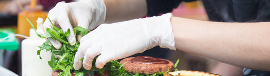 person prepping a burger while wearing white latex gloves